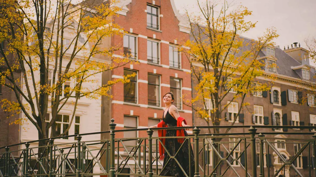 Couple posing beside a tulip bed on a custom Amsterdam photoshoot with canal houses behind, Amsterdam
